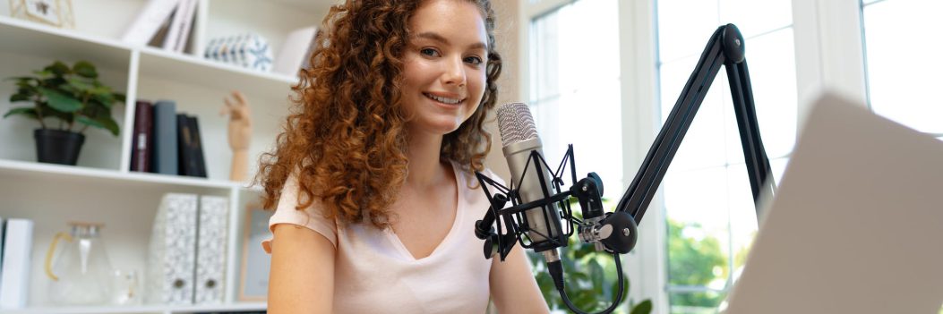 52476648_woman-vlogger-looking-at-laptop-and-recording-video-with-microphone